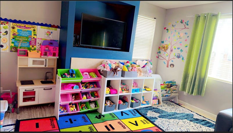 Playroom with toy kitchen, storage shelves, and colorful rug