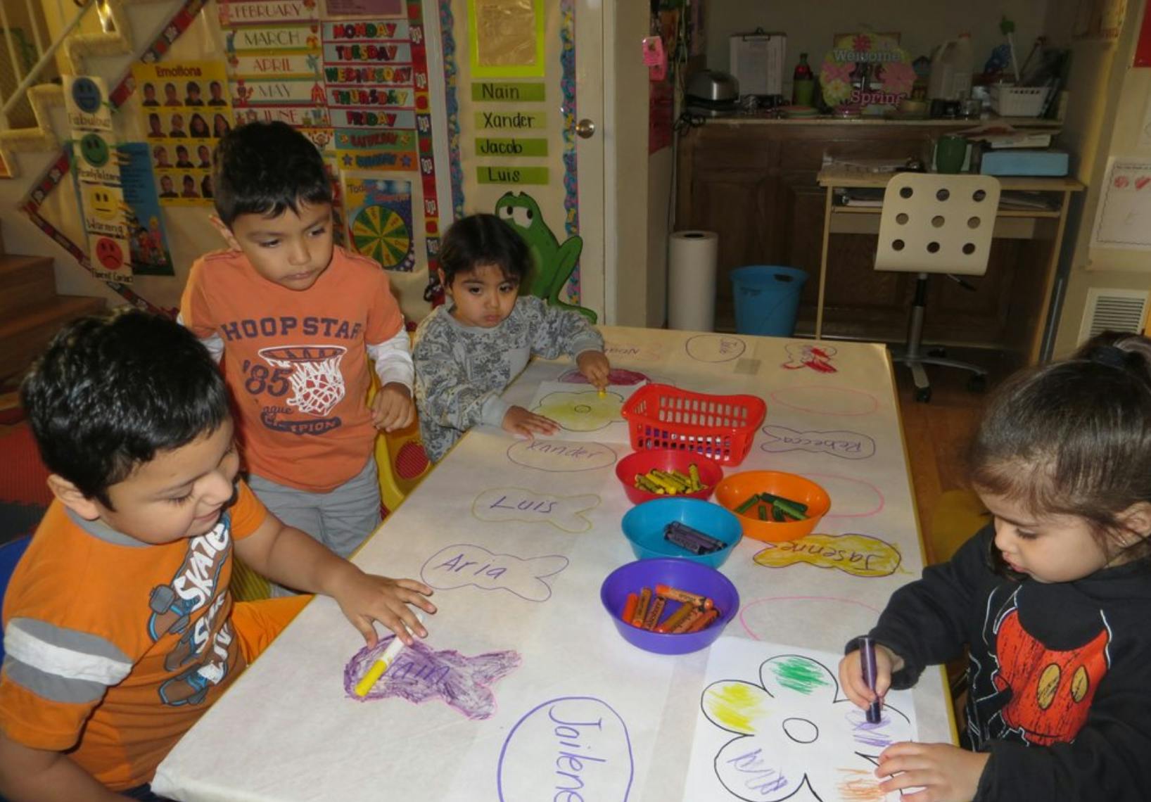 Four children drawing and coloring at a table