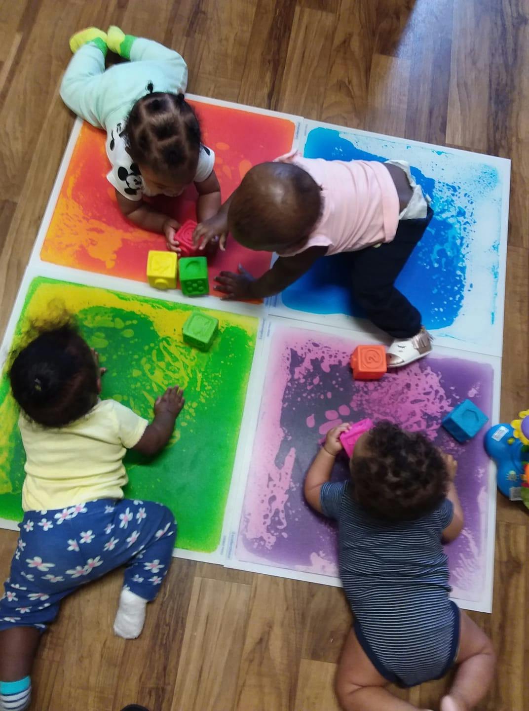 Four children playing with blocks on colorful gel mats