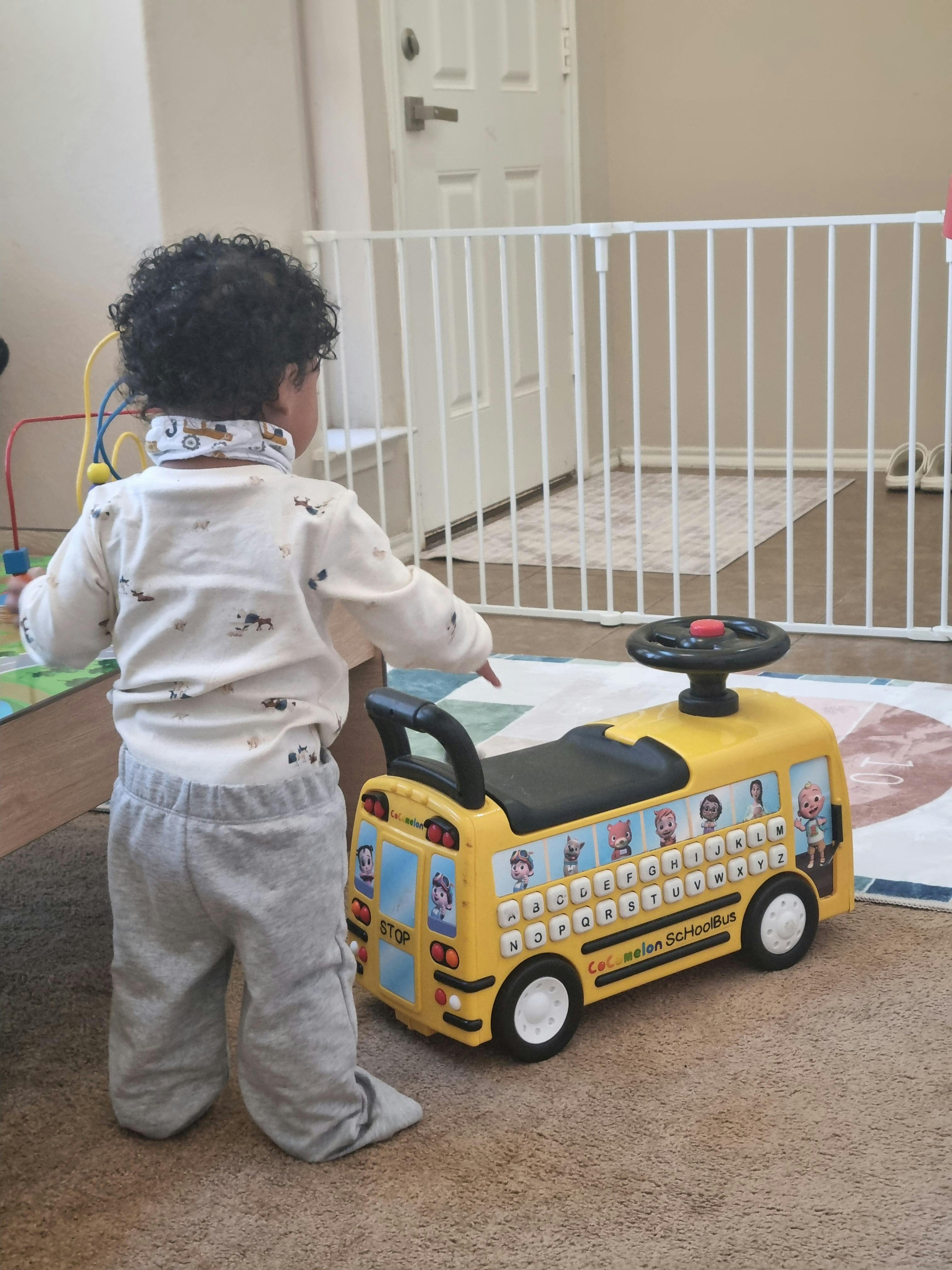 Child standing next to a yellow toy bus