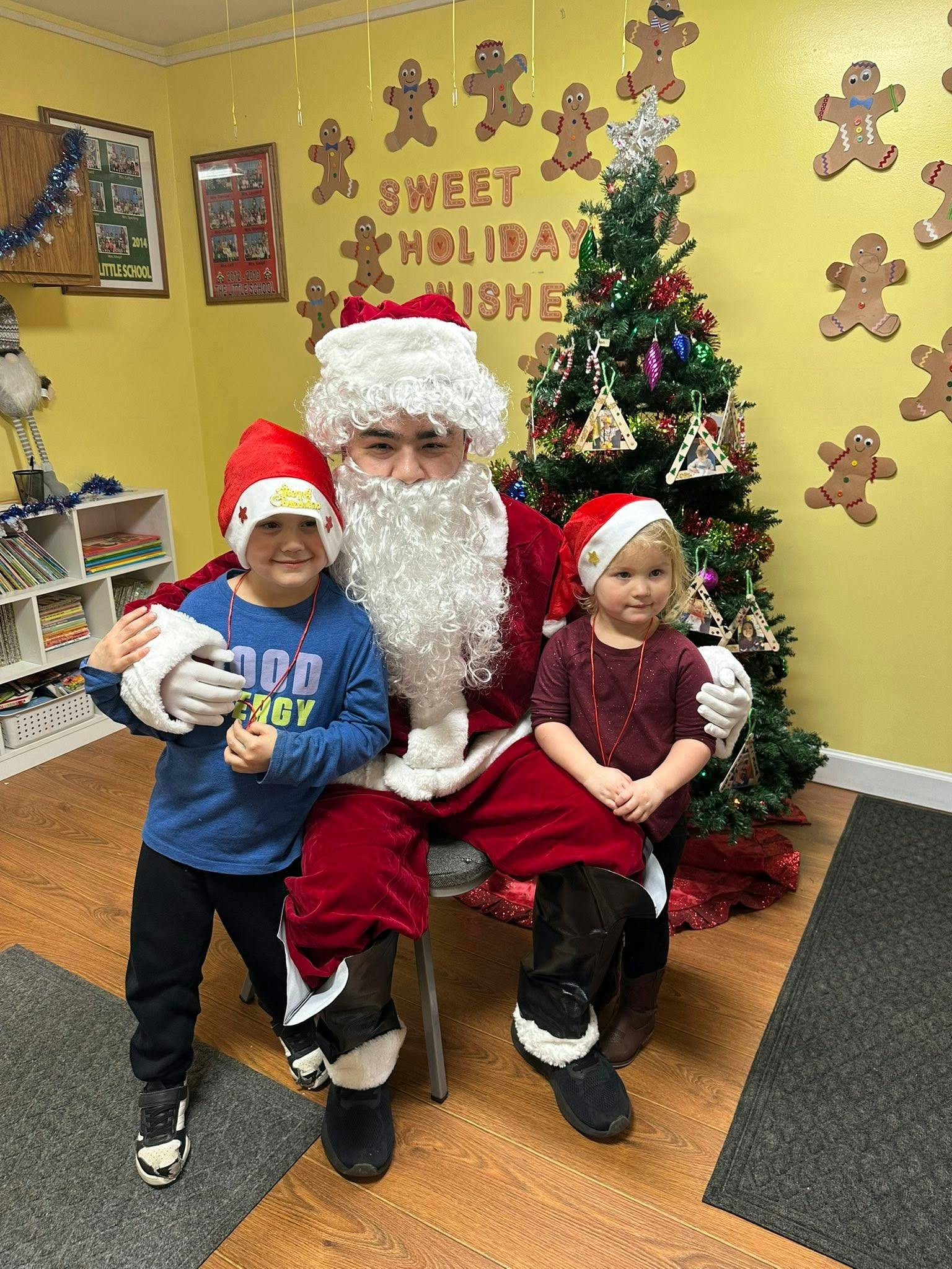 Santa Claus sitting with two children in front of a holiday tree
