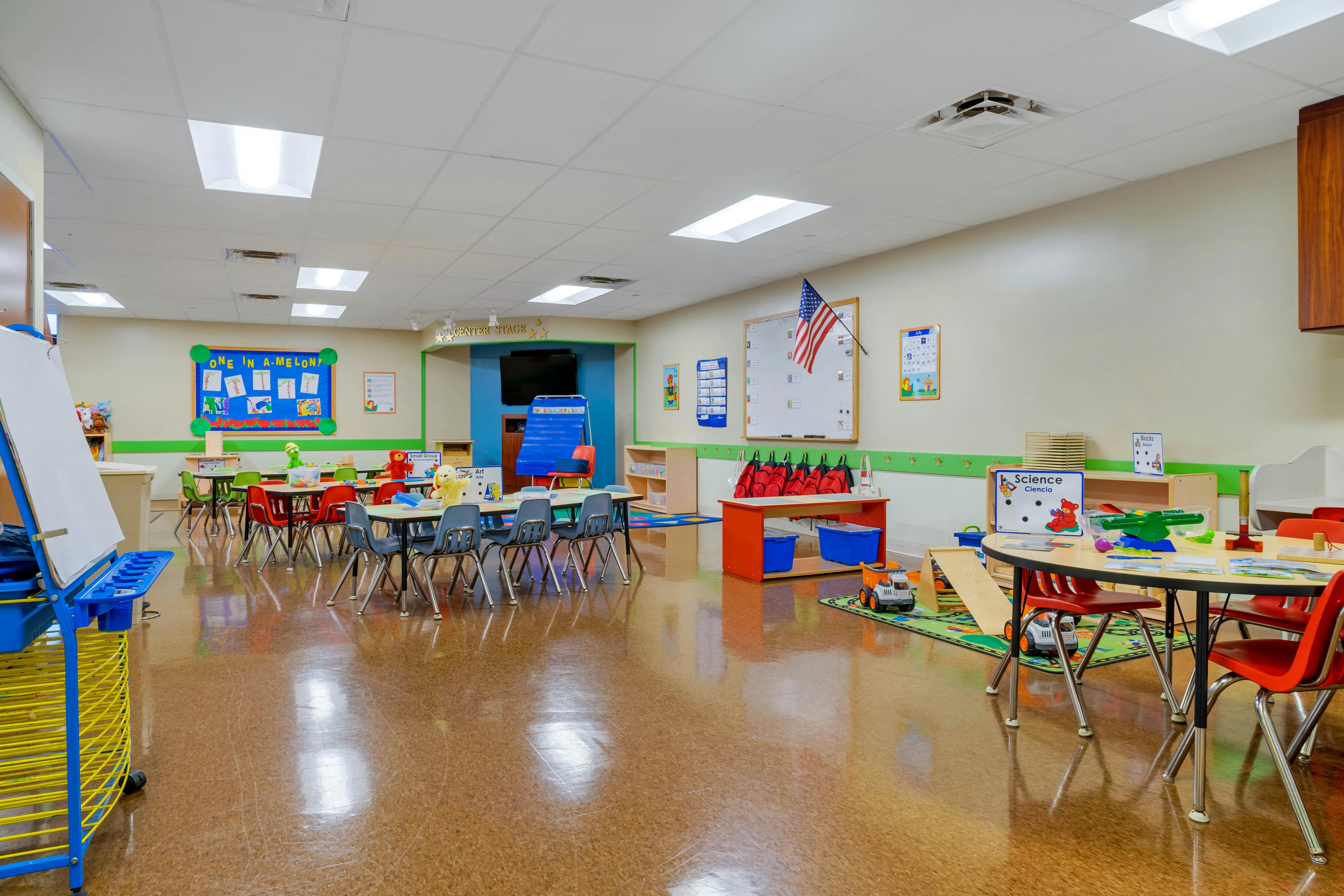 An empty early childhood classroom with small tables and chairs