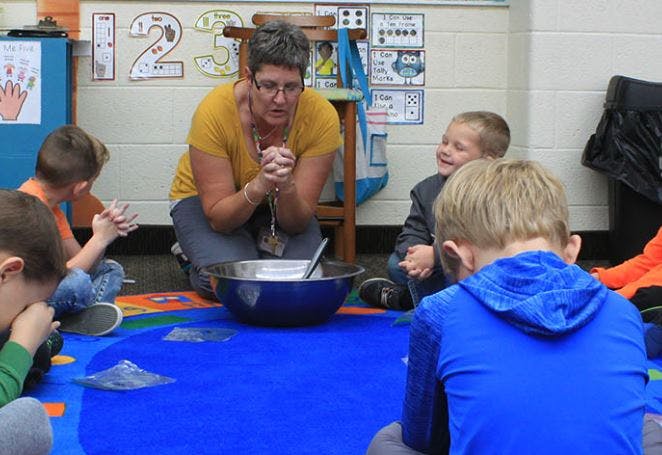 Adult and children sitting on floor in classroom