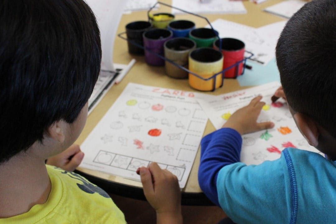 Two children working on papers at a table