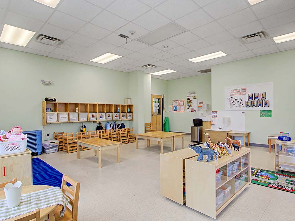Classroom with small tables and chairs, cubbies, and toys
