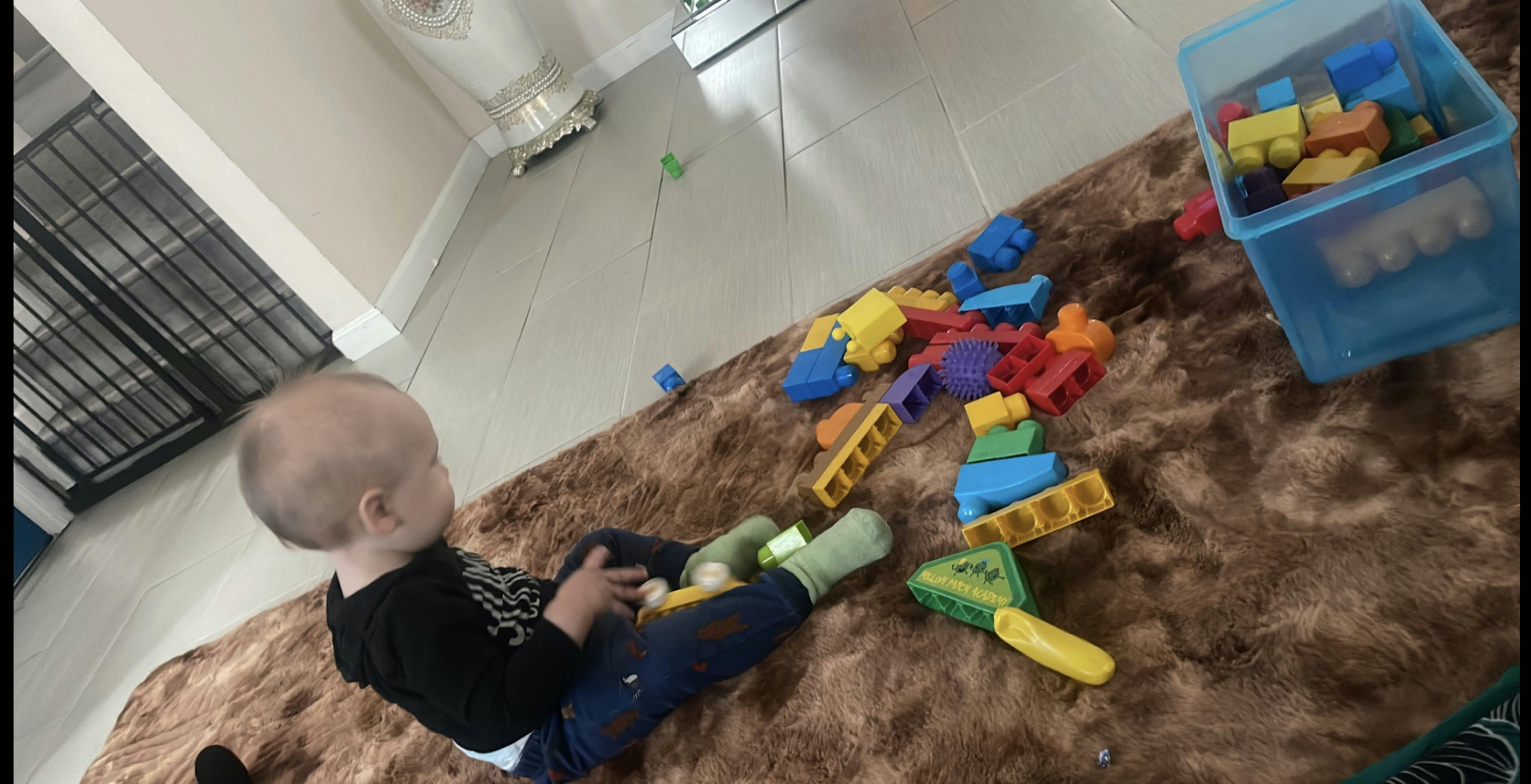 Child sitting on a rug with building blocks
