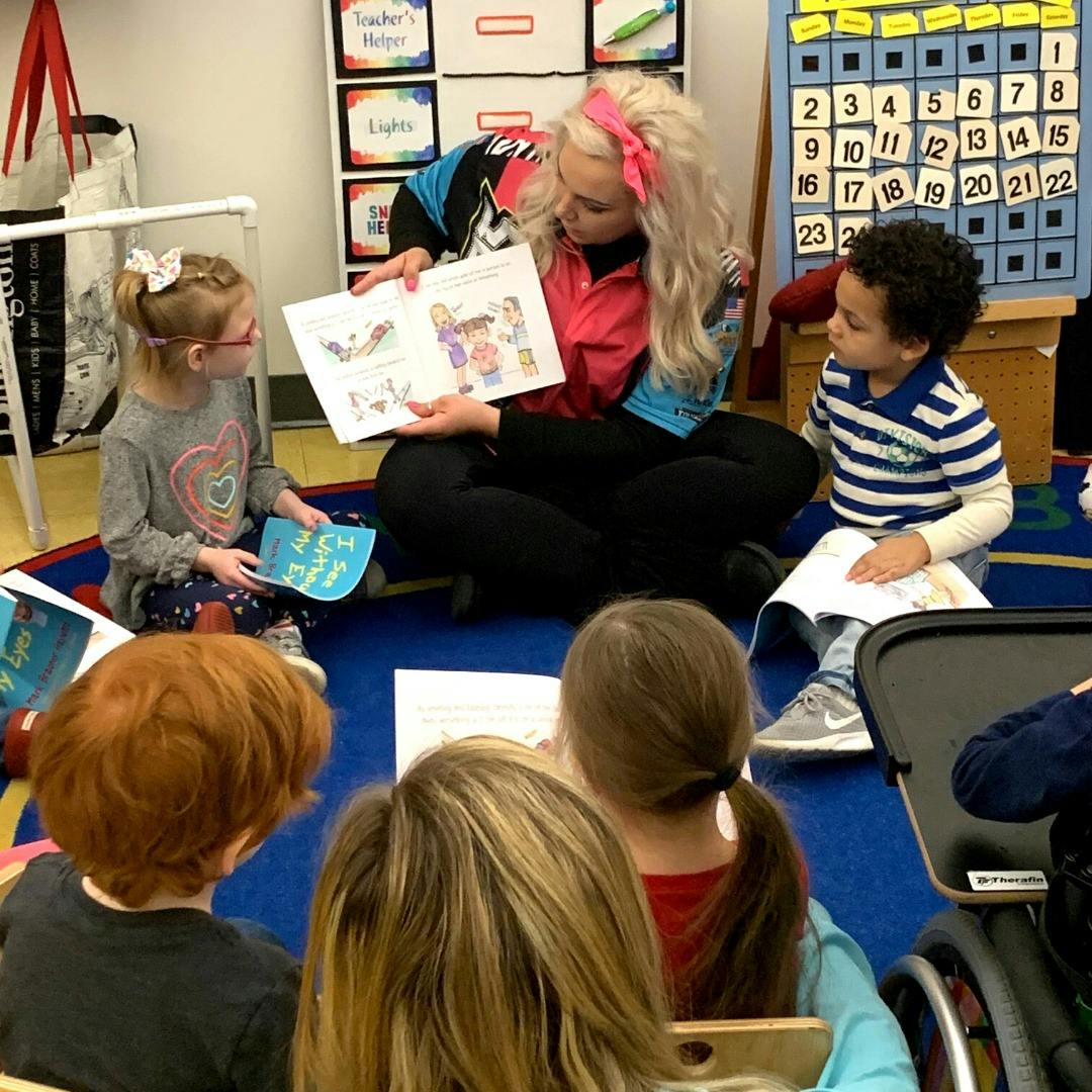 Person reading a book to children in a classroom