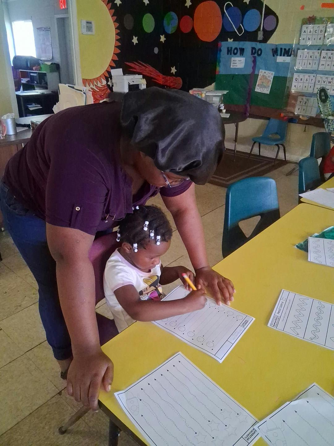 Adult and child doing a tracing activity at a yellow table