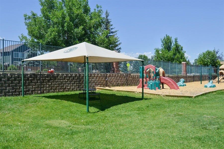 Canopy over grass next to a playground with slides and sand