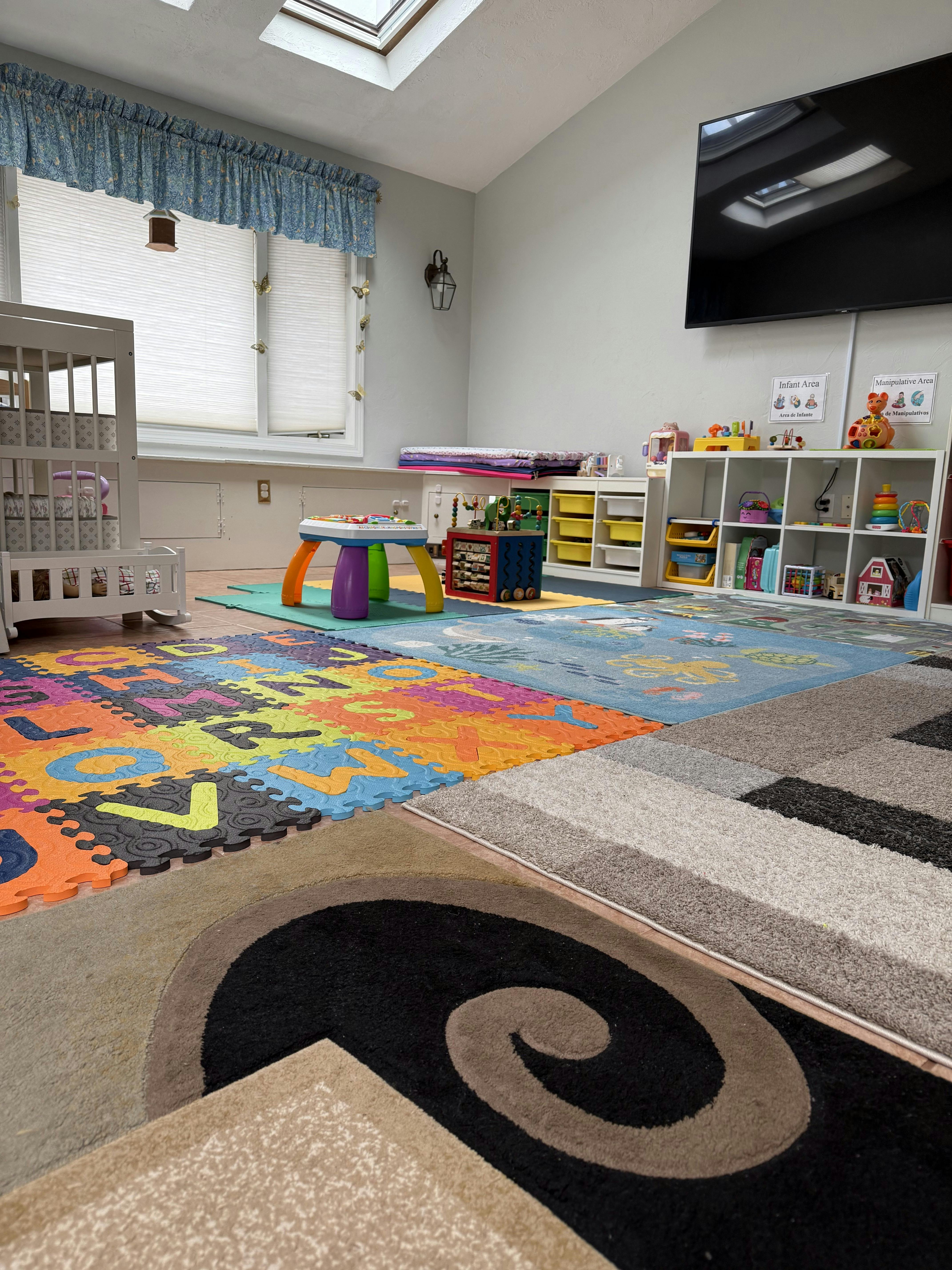 Playroom with colorful alphabet floor mats, crib, and shelves of toys