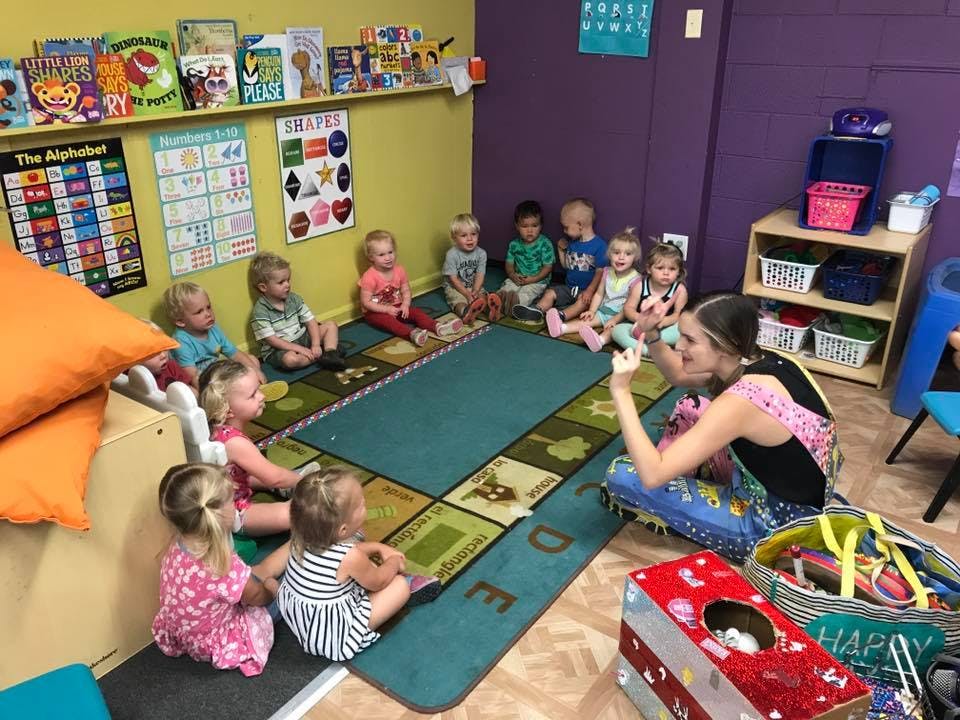 Adult and children sitting on a rug in a classroom