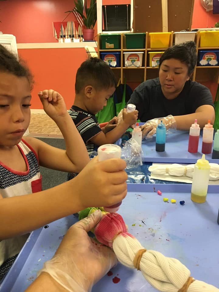 People tie-dyeing fabric with colorful dyes