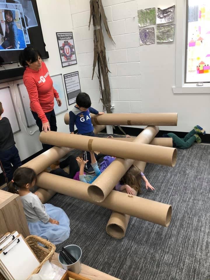 Adult and children playing with large cardboard tubes