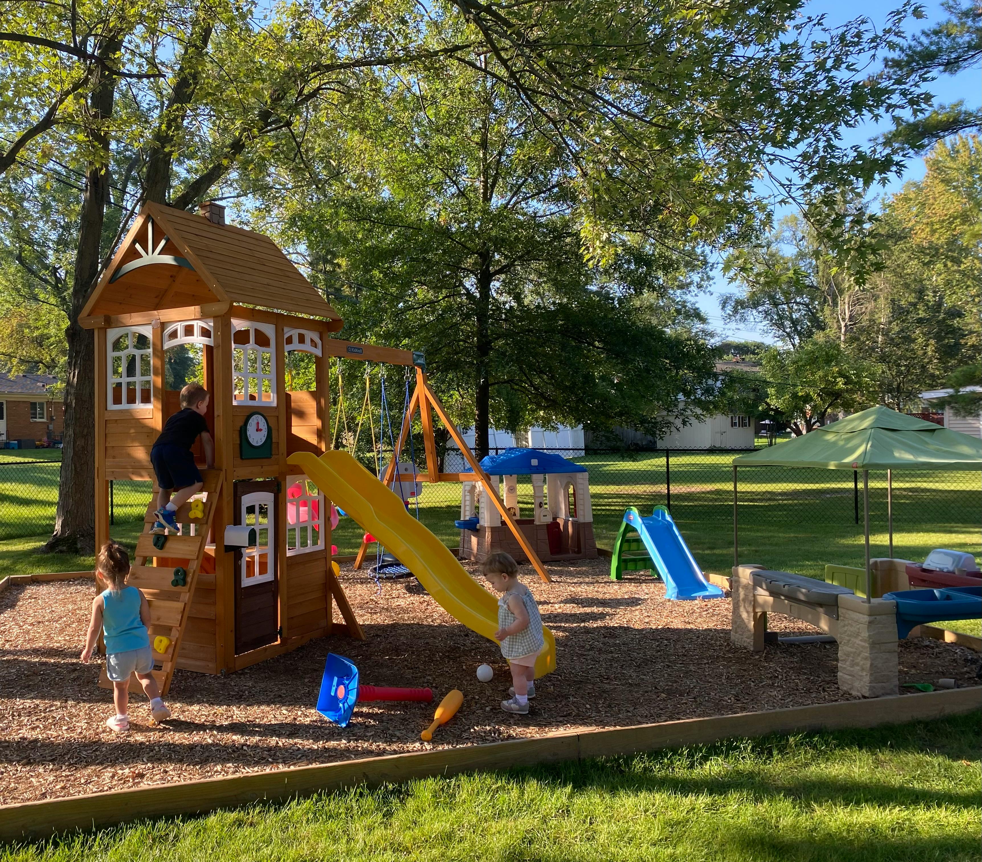 Children playing on a wooden playset with slides and swings