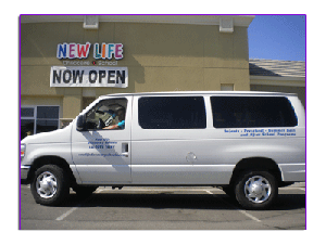White van parked in front of a building with a "NOW OPEN" sign