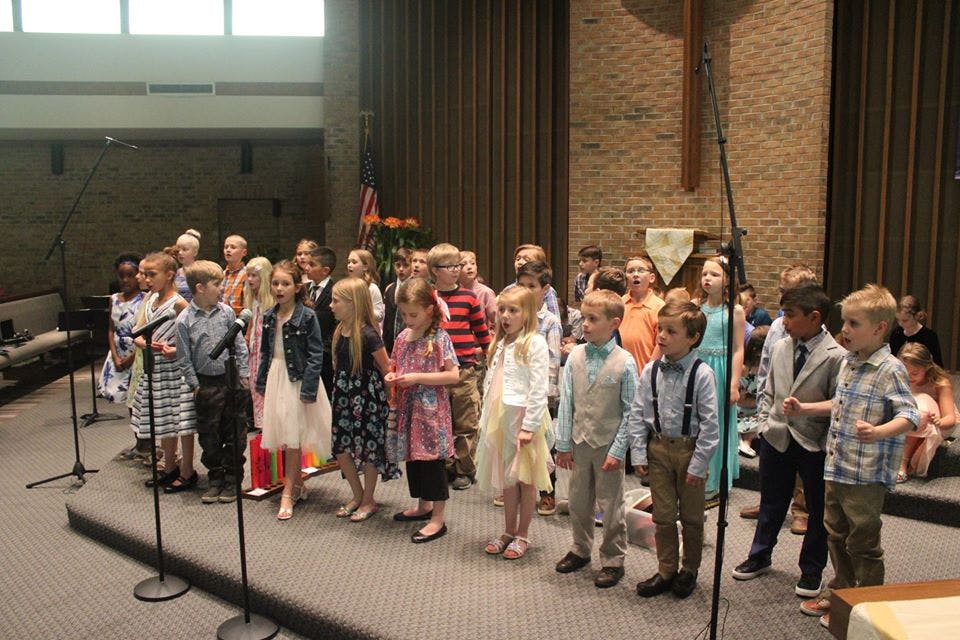 Group of children standing on a stage with microphones