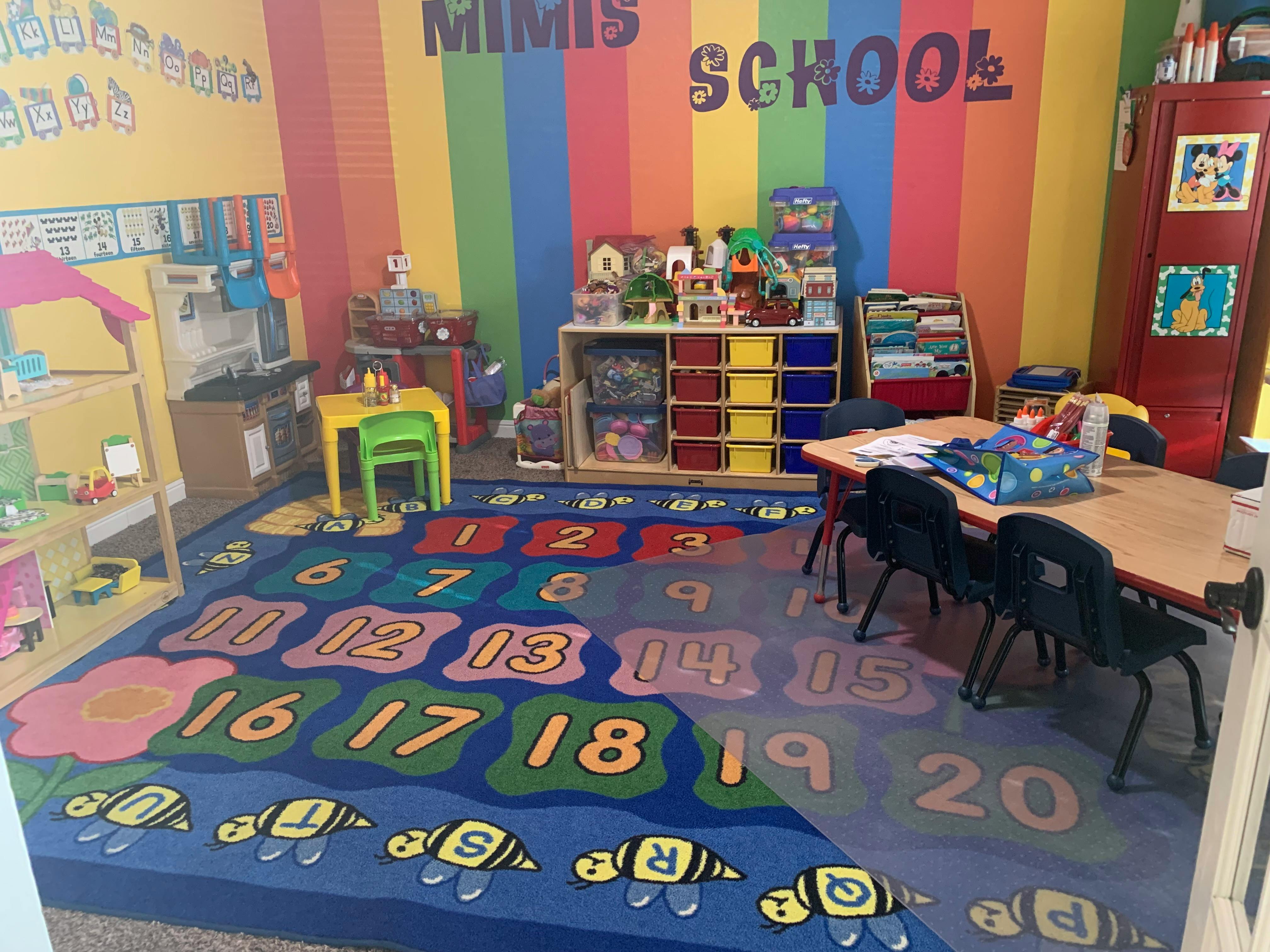 A colorful classroom with a number rug and small tables