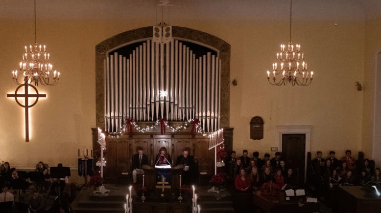People performing in a church with an organ and chandeliers