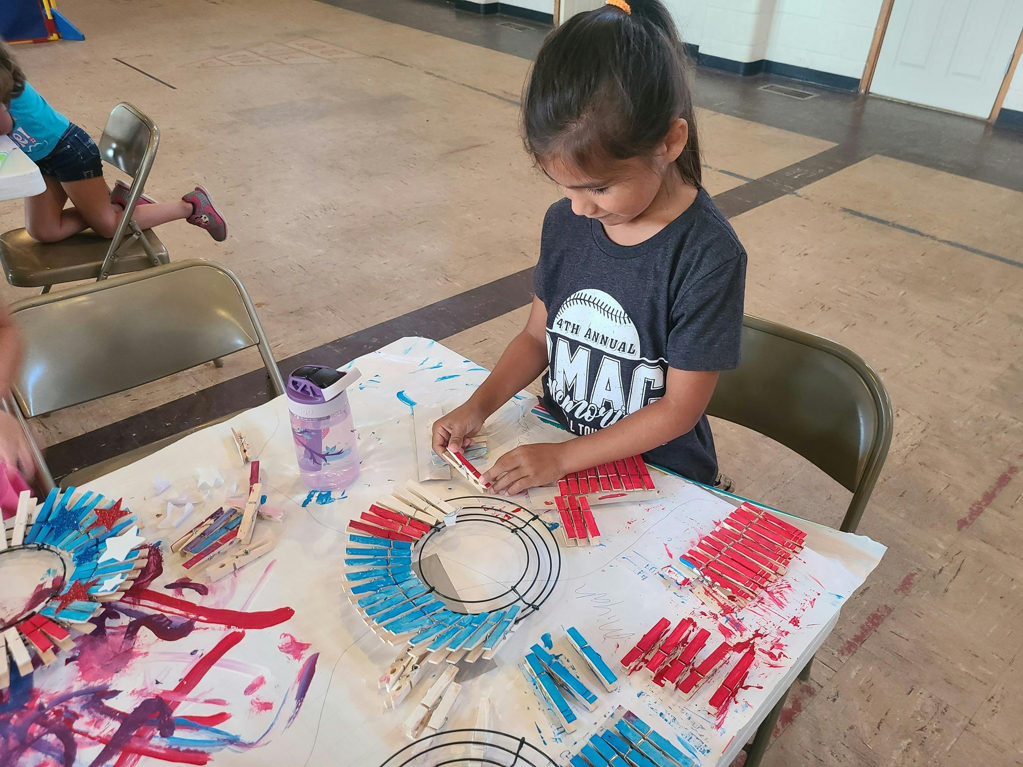 Child making a craft with clothespins and a wire frame