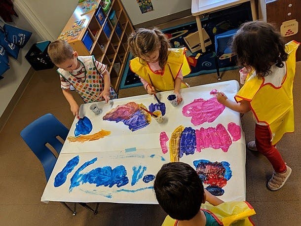 Children painting at a table in a classroom