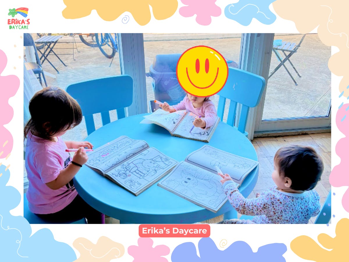 Three children coloring in books at a round blue table