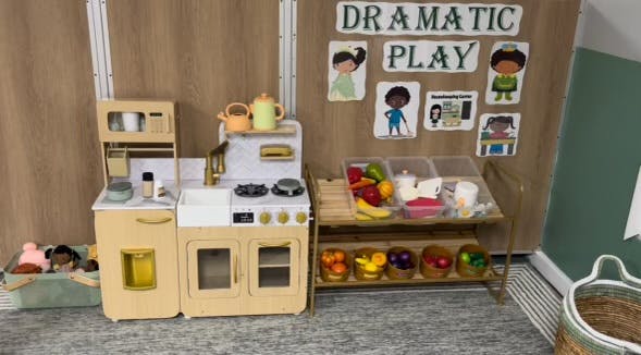 Play kitchen with toy food and a sign that says "Dramatic Play"