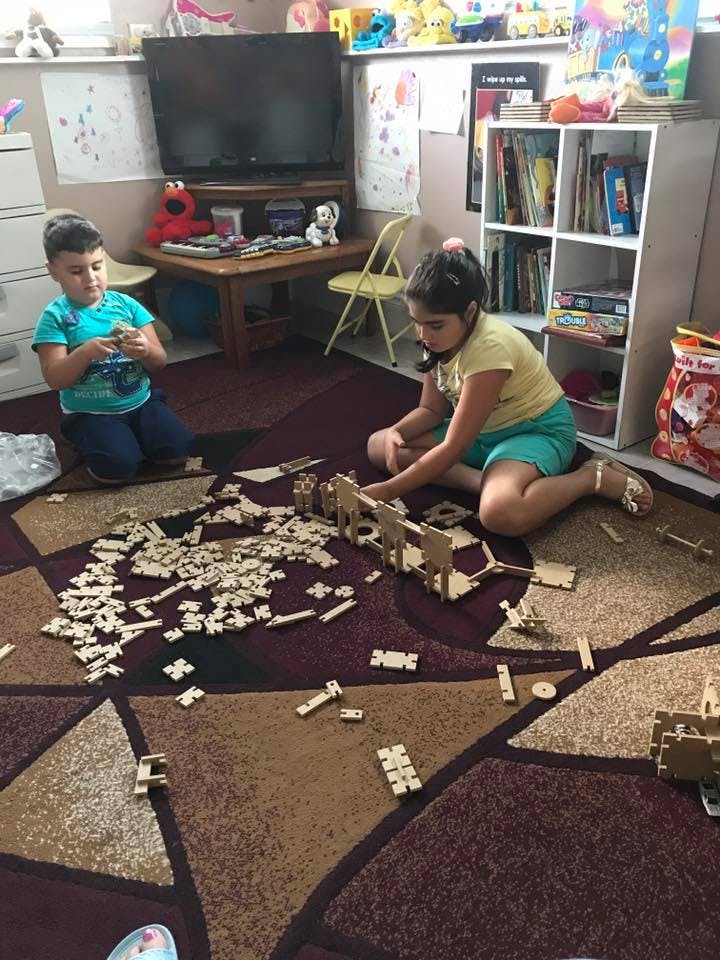 Two children playing with wooden building blocks on a rug