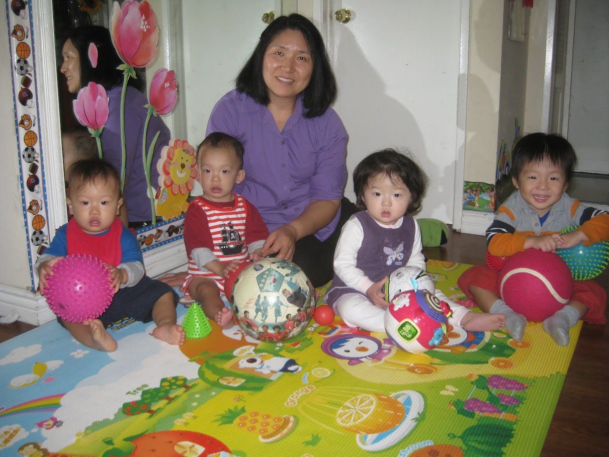 Adult and four children sitting on a playmat with balls