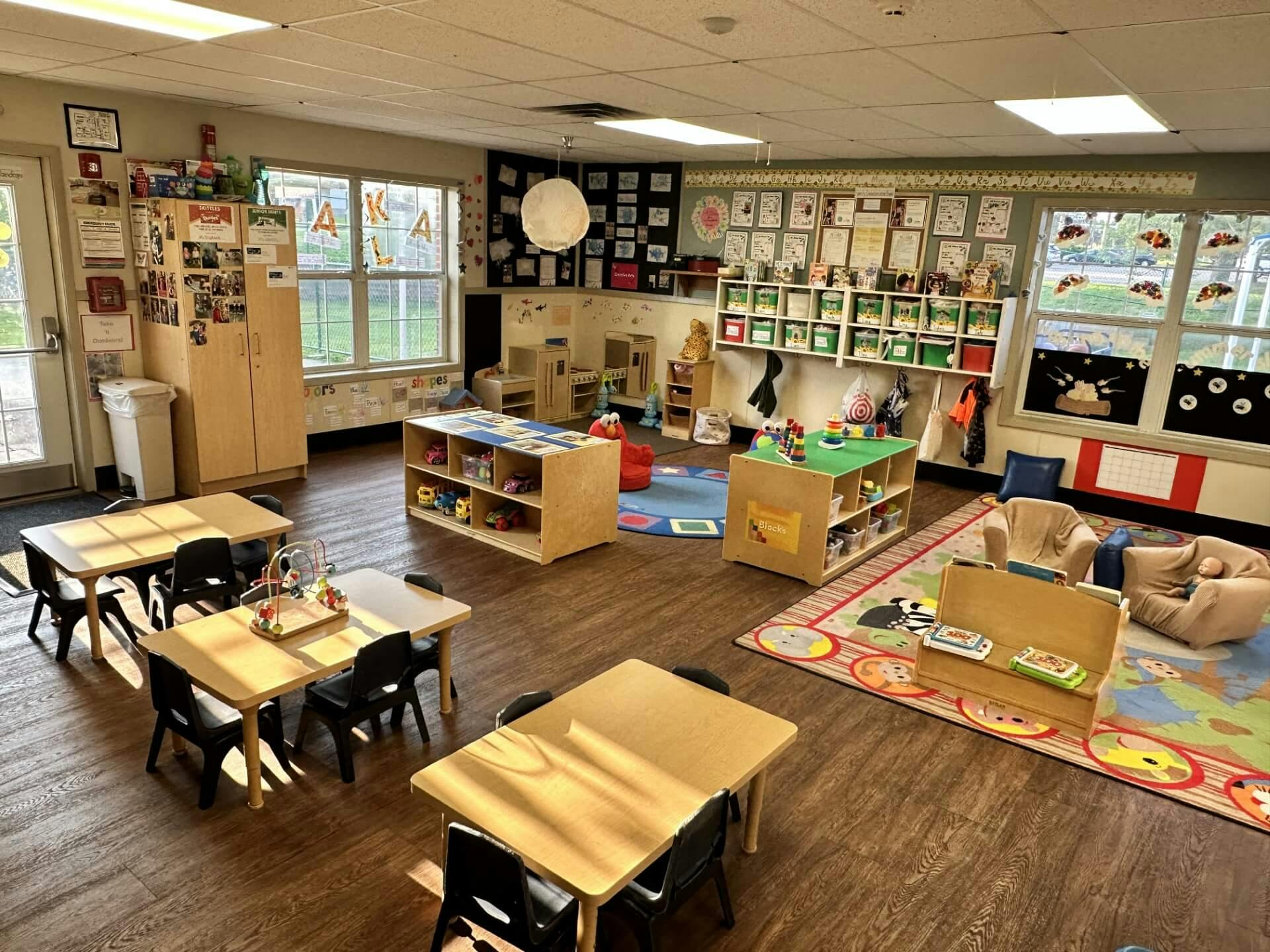An empty early childhood classroom with small tables and chairs