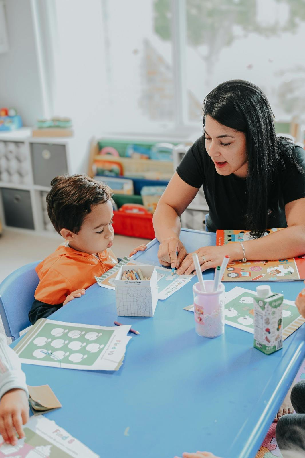 Person and child at a table with papers and art supplies