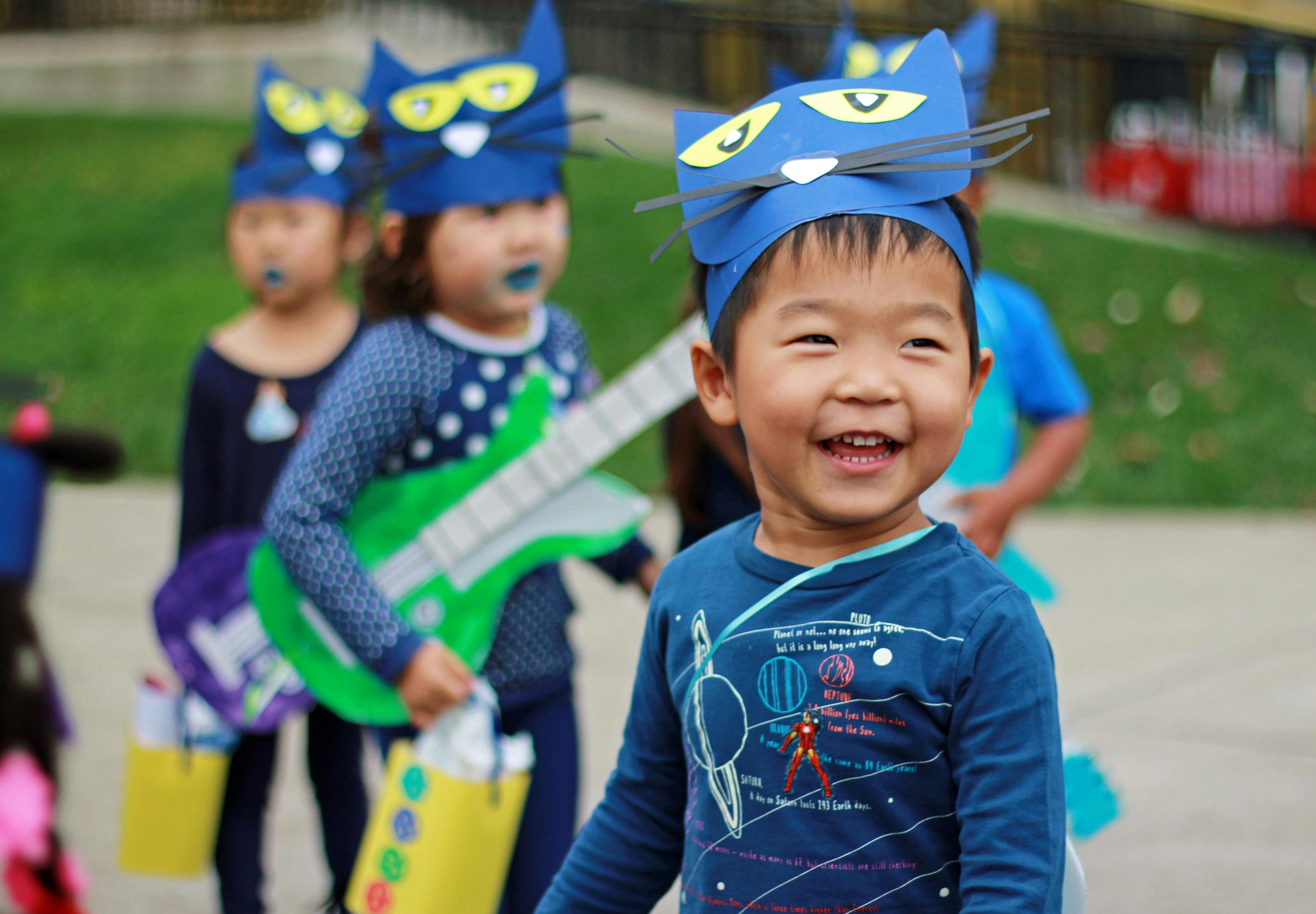 Child in a blue cat costume smiling, smiling