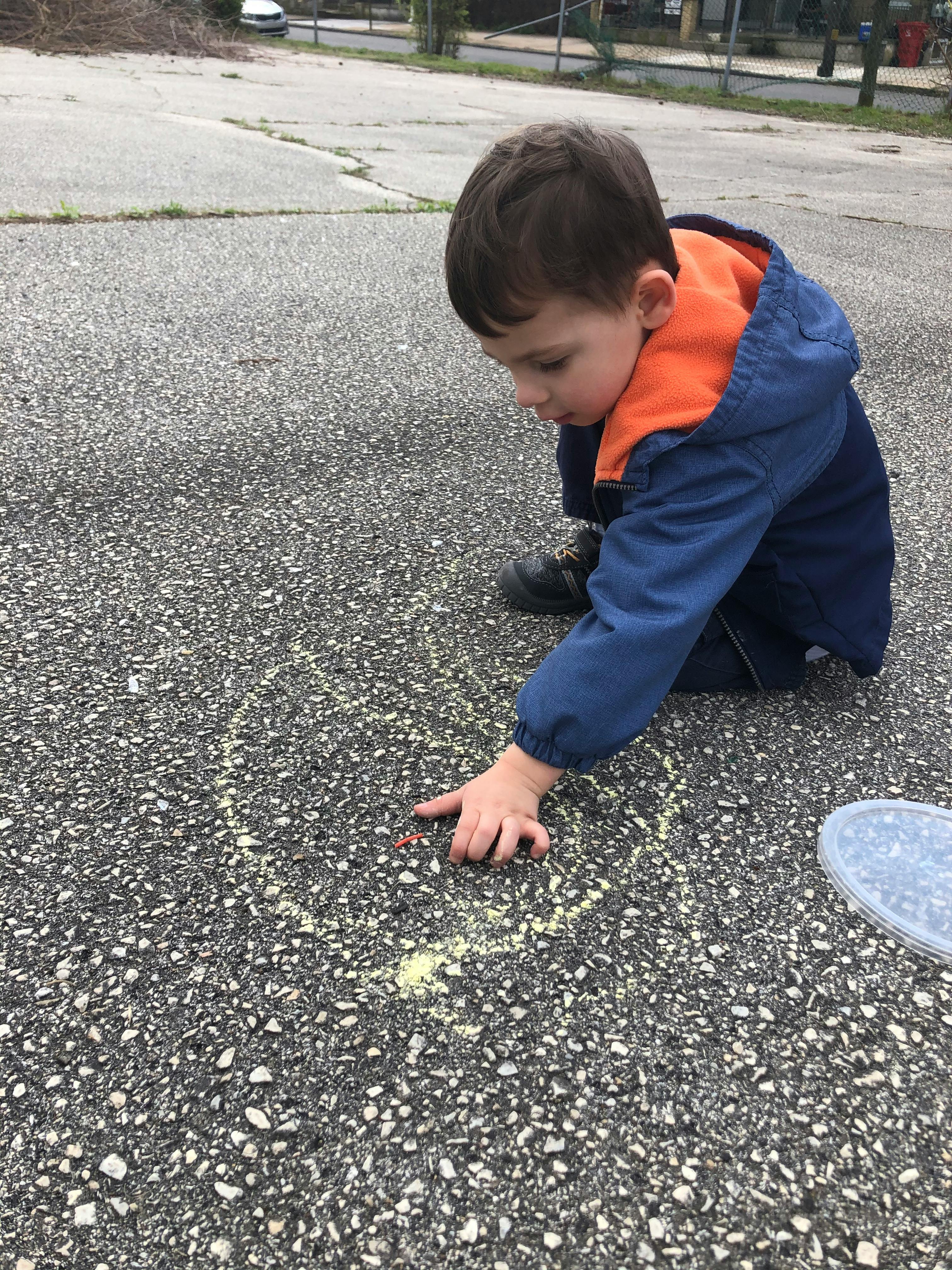 Child drawing with chalk on pavement