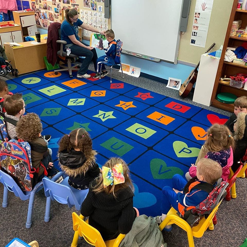 Adult reading a book to children in a classroom