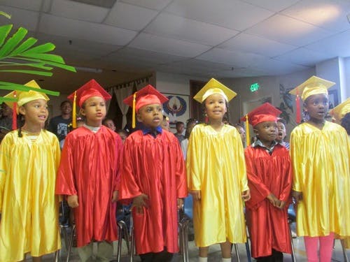 Children in red and yellow graduation caps and gowns