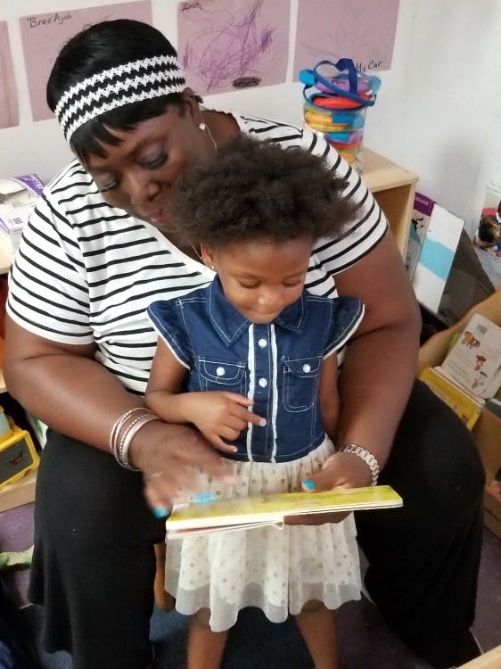 Person and child reading a book together
