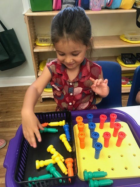 Child playing with colorful pegs and a pegboard