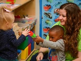 Adult and two children playing with blocks