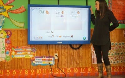 Person standing next to an interactive display in a classroom