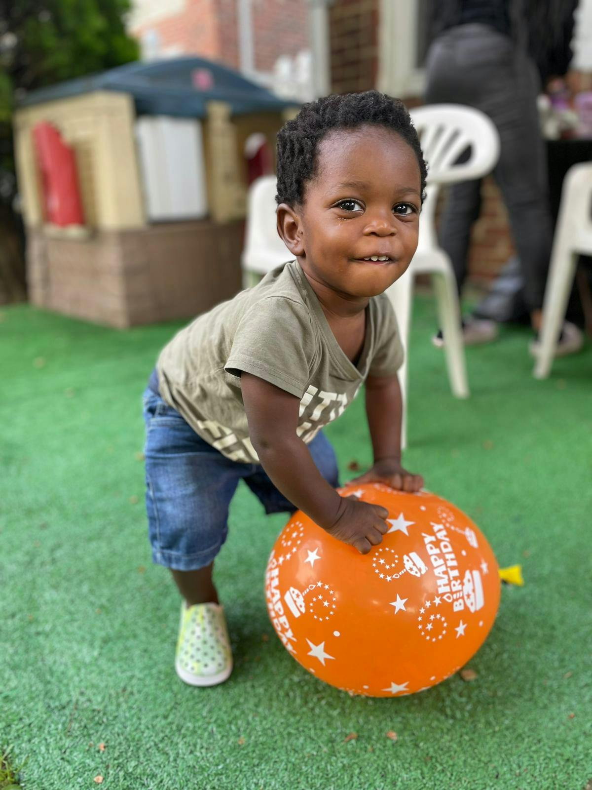 Child playing with an orange Happy Birthday balloon