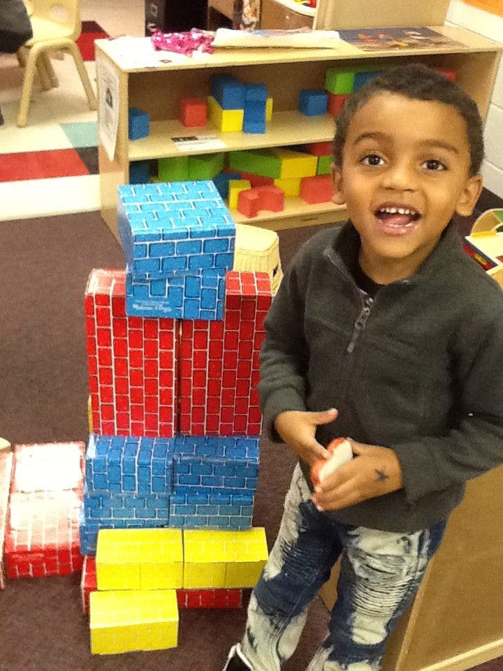 Child standing next to a structure made of large blocks