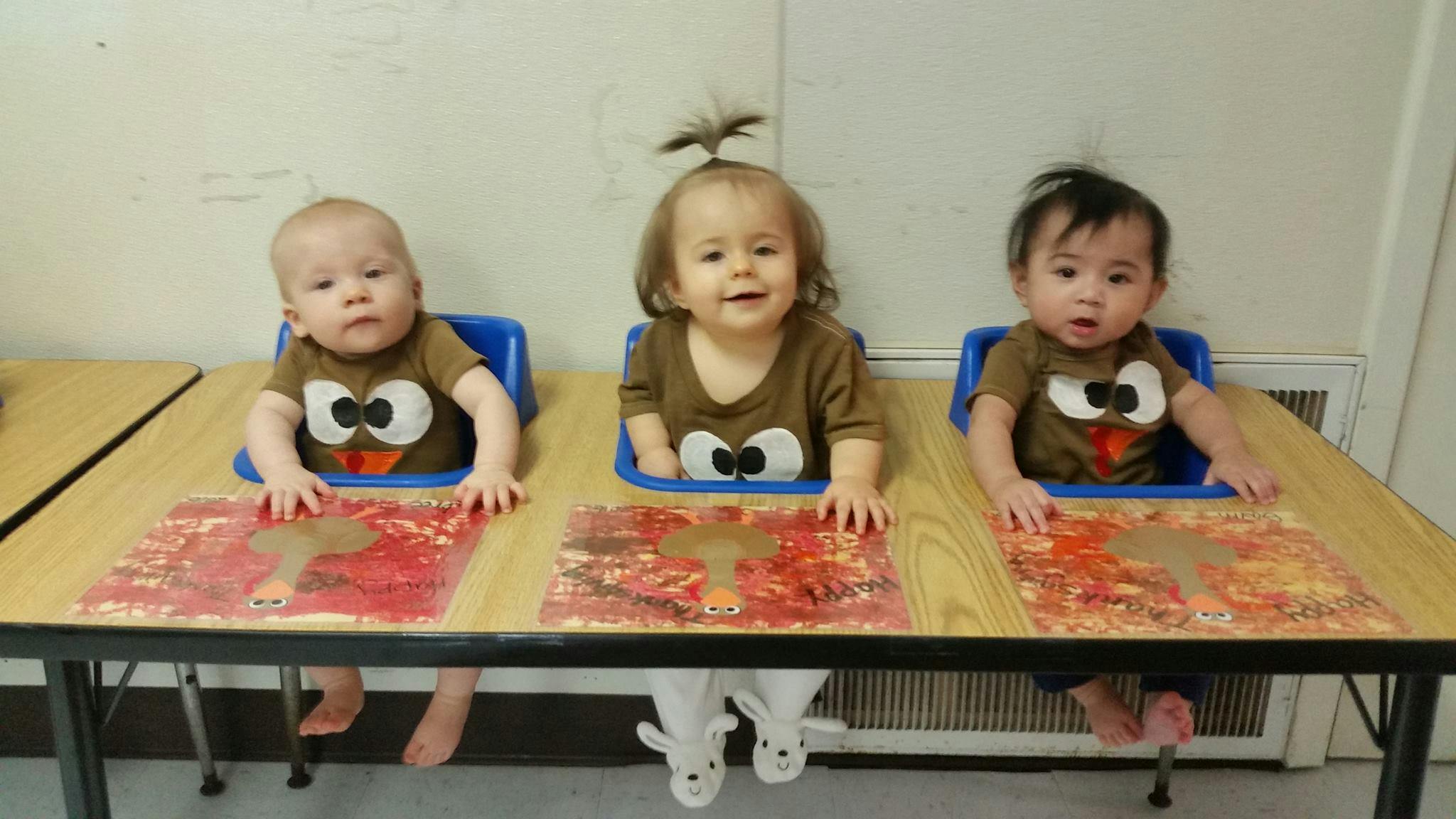 Three children in high chairs at a table