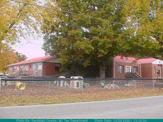 Two single-story buildings with red roofs behind a chain-link fence