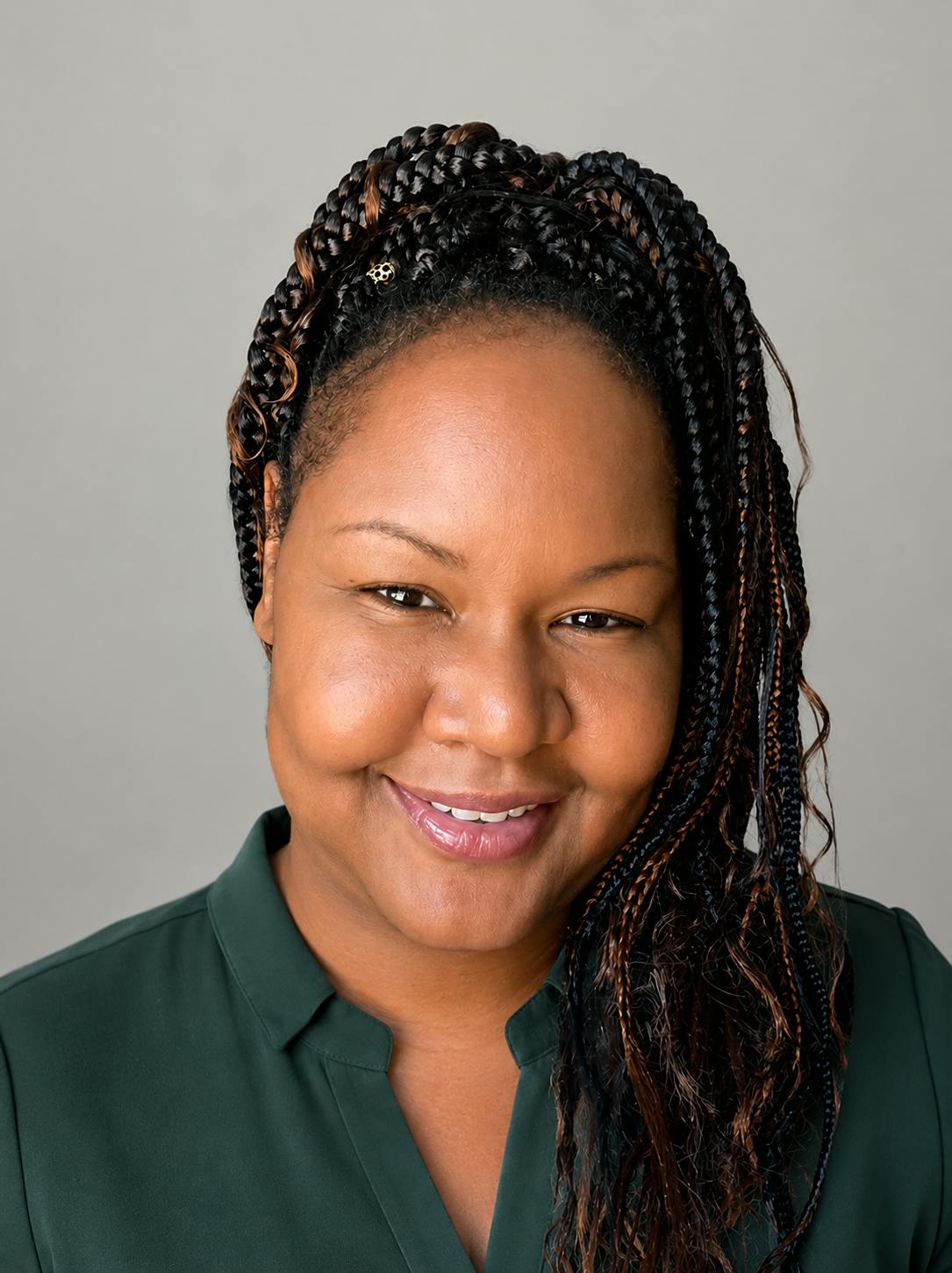 Close-up portrait of a person with braided hair against a gray background