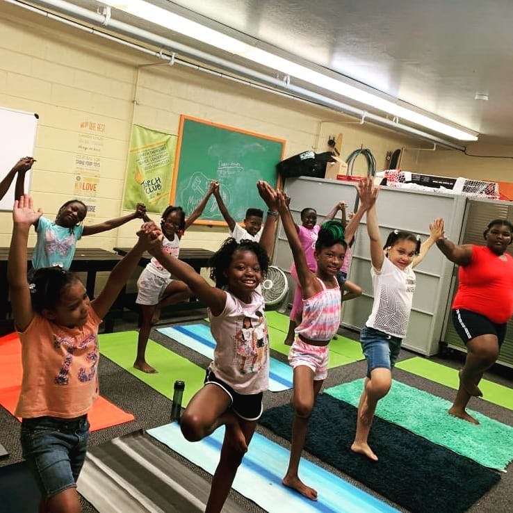 Children and adults doing yoga poses in a classroom