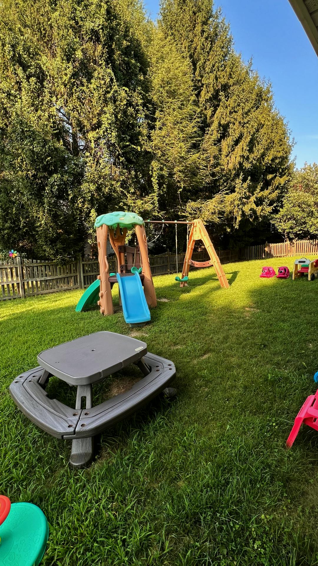 Backyard with a play structure, swing set, and picnic table