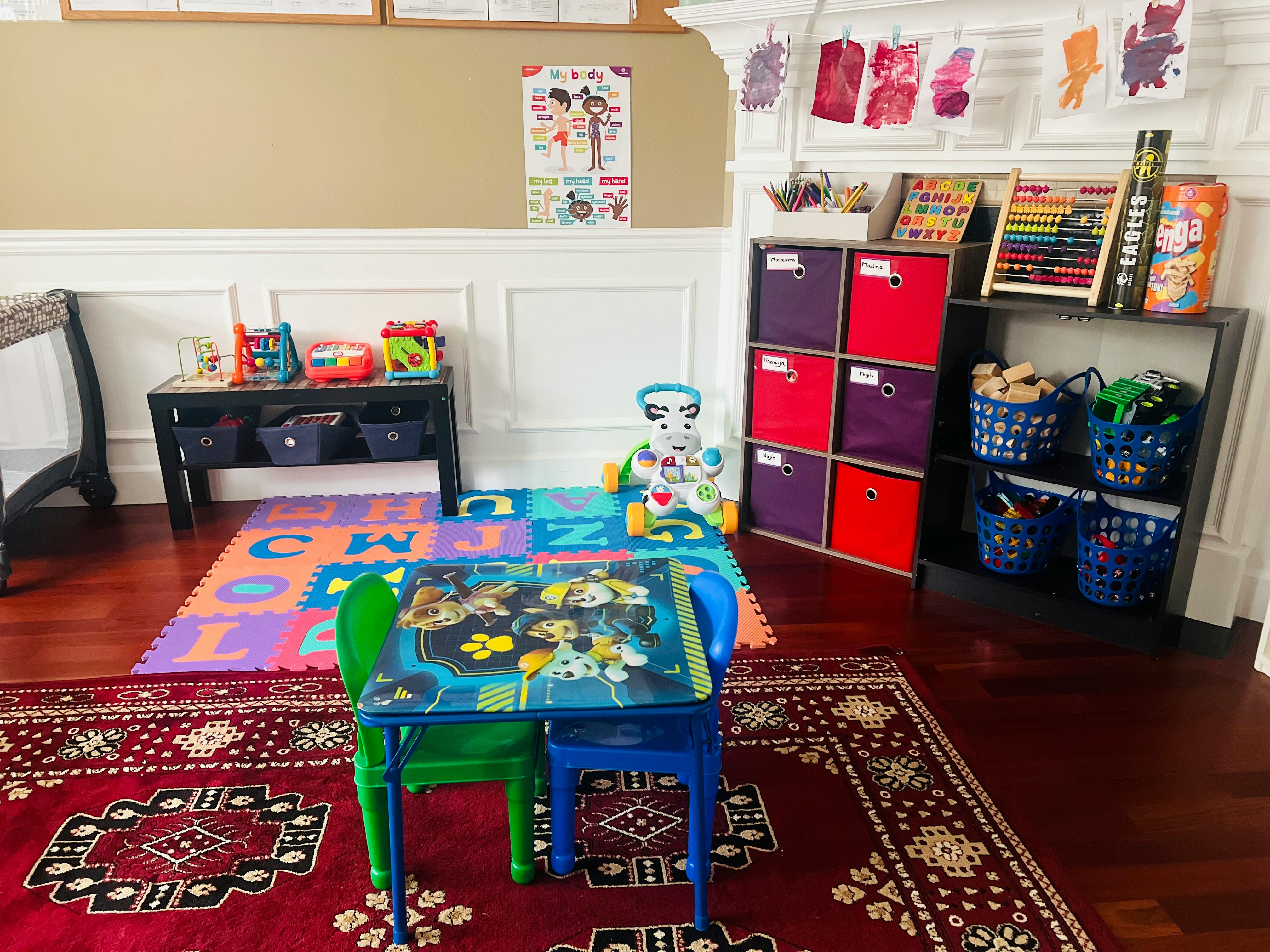 Playroom with a small table and chairs, alphabet mat, and toy storage
