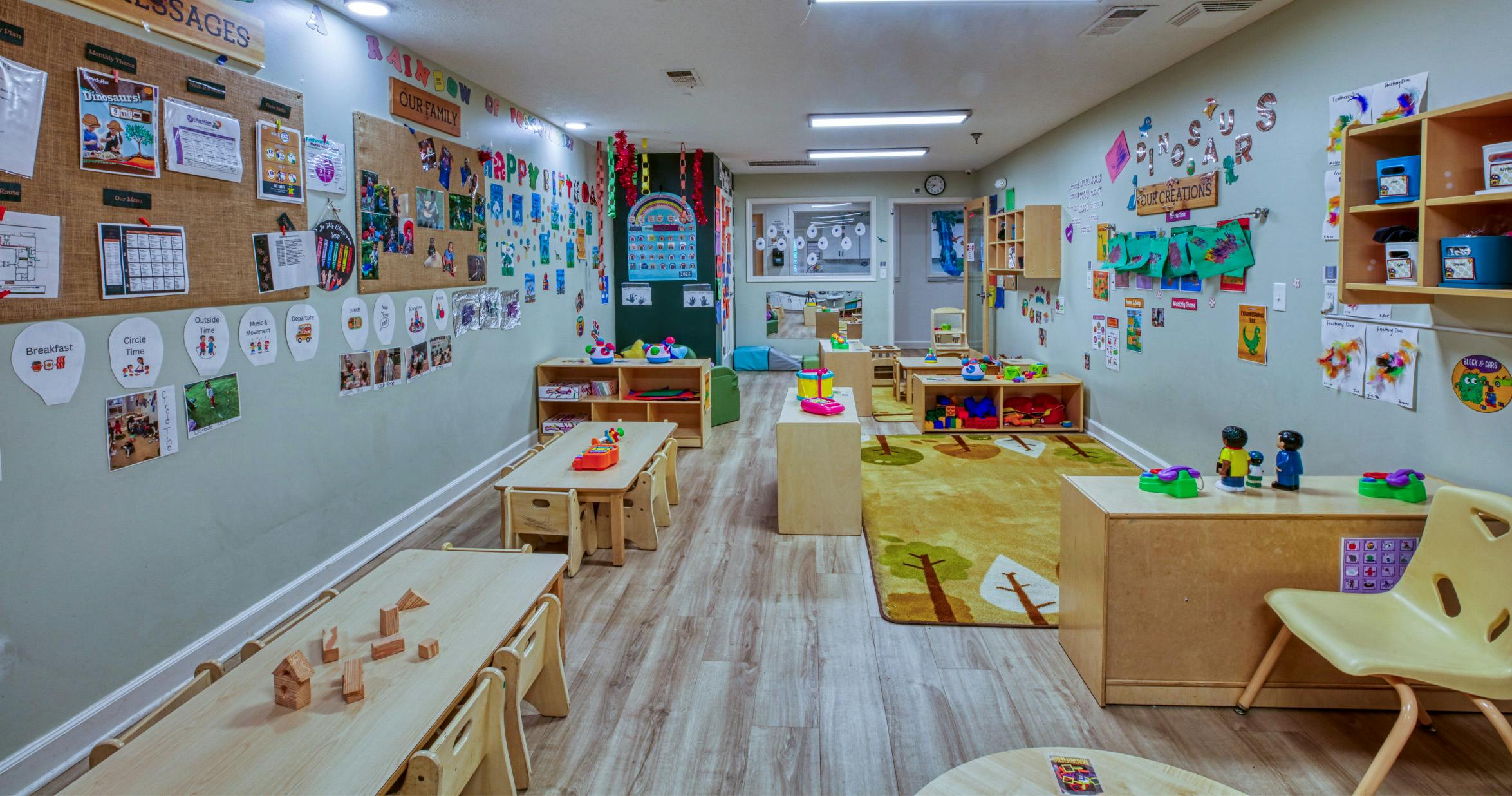 An empty early childhood classroom with several tables, chairs, and shelves