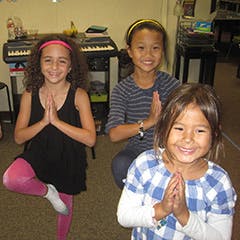 Three children doing yoga poses indoors