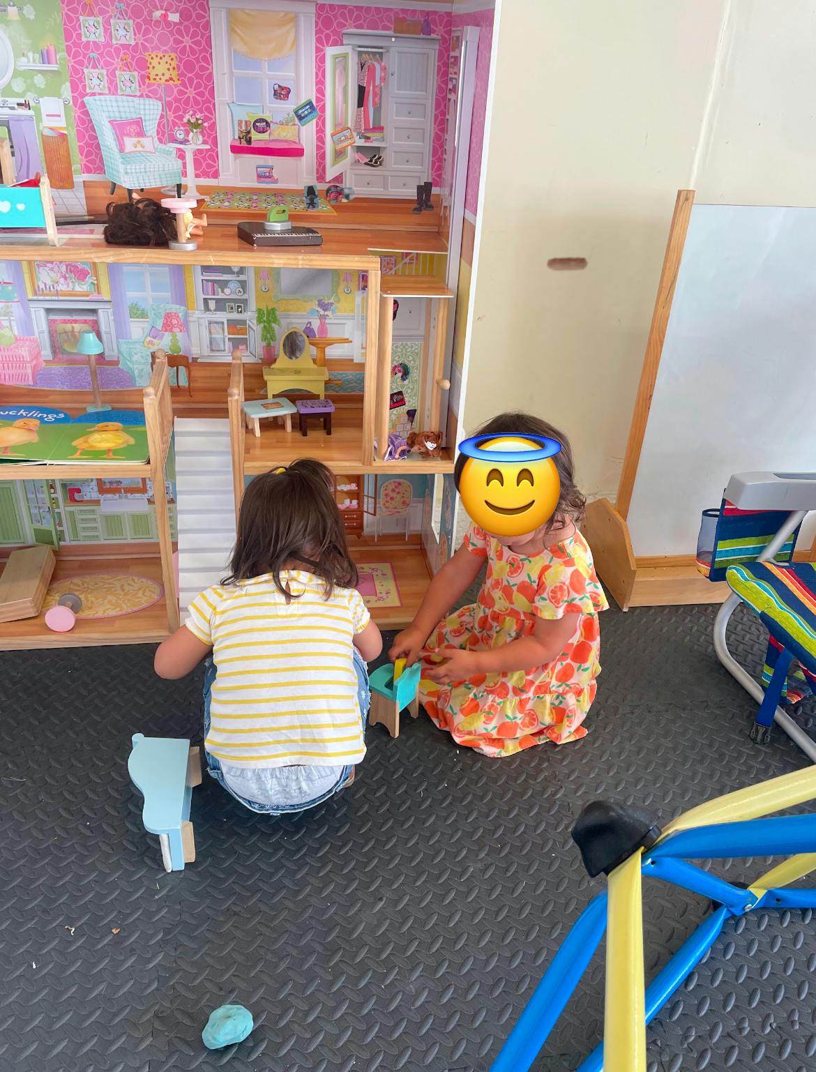 Two children playing with a dollhouse