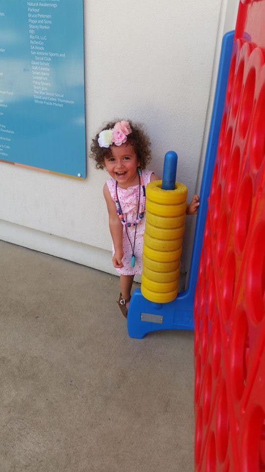 Child standing next to a large ring toss game